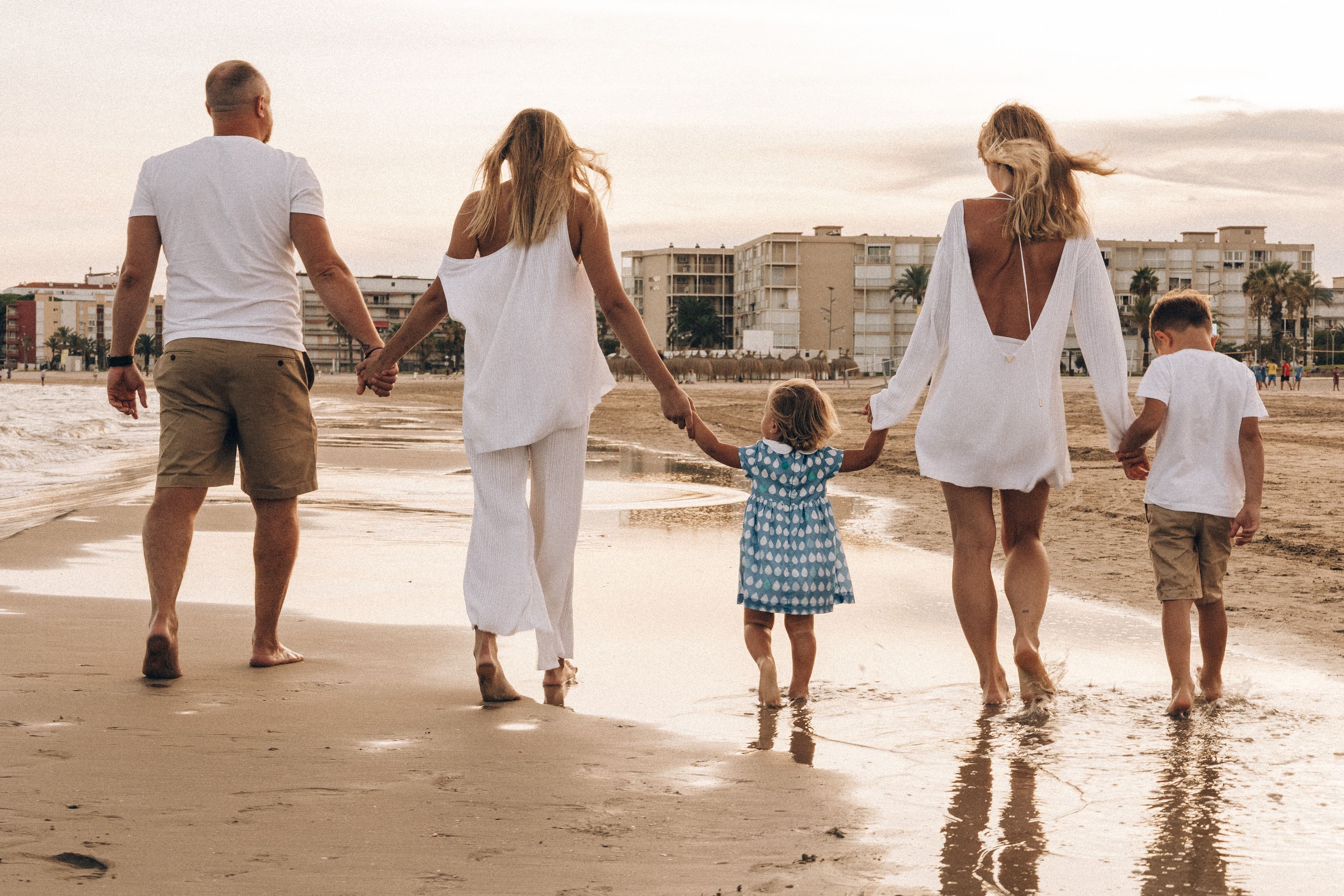 Family walking together on the beach at sunset